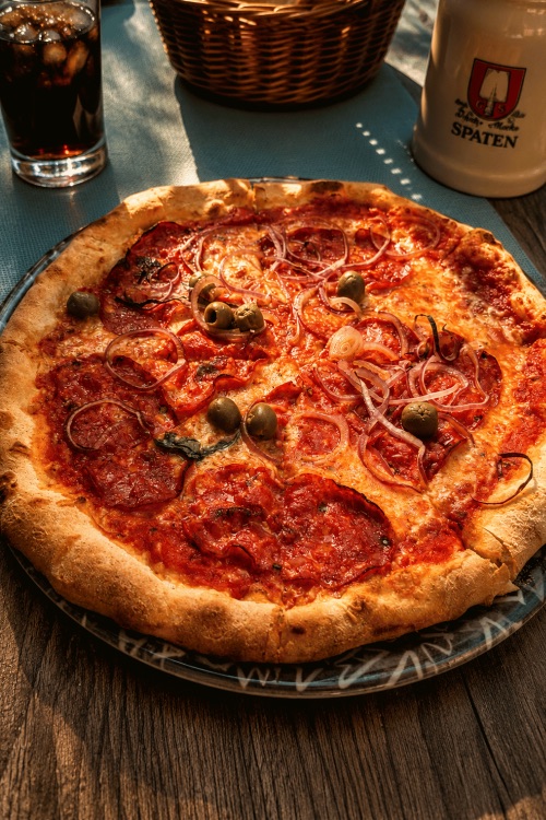 Pizza mit scharfer Salami, Oliven und roten Zwiebeln